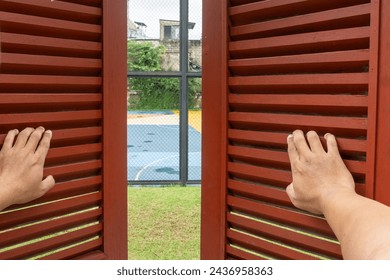 two hands open the shutters. opening two old traditional wooden window shutters to let in the sunlight - Powered by Shutterstock