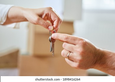 Two hands pass a house key as a symbol of real estate and house buying - Shutterstock ID 1898416264