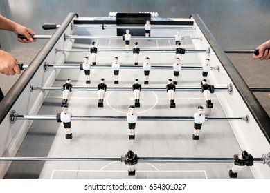 Two hands of two people playing Table Football in relax times for entertainment.