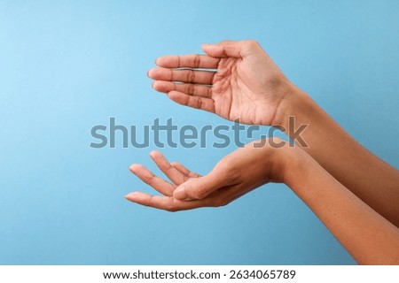 Two Hands Posed As If Presenting Or Catching Something Against Blue Background