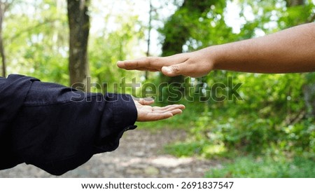 Two hands are positioned parallel to each other, one palm up and one palm down