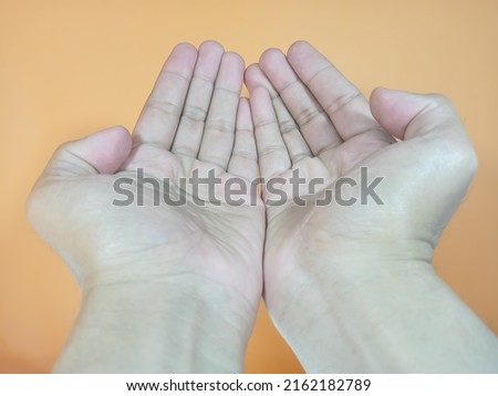 two hands praying on an orange background