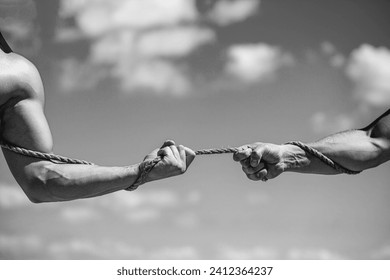 Two hands pull the rope against the background of the sky. Rope, cord. Hand holding a rope, climbing rope, strength, determination. Rescue, help, helping gesture or hands. Black and white.