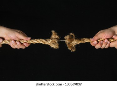 Two Hands Pulling Frayed Rope On Black Background