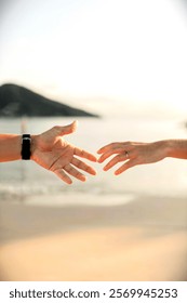 Two hands reaching toward each other against a serene beach backdrop, symbolizing connection and intimacy.