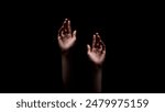 Two hands reaching up towards the dark, unknown, or possibly a source of light, suggesting a sense of hope or desperation, appear to be reaching out for something.