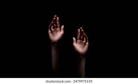 Two hands reaching up towards the dark, unknown, or possibly a source of light, suggesting a sense of hope or desperation, appear to be reaching out for something. - Powered by Shutterstock