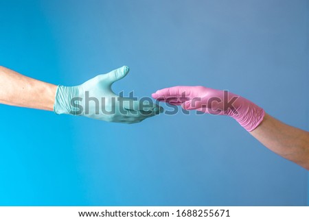 Two hands in rubber medical gloves. Romantic relationships between people. Protection, isolation and distance during the Covid-19 coronavirus pandemic.