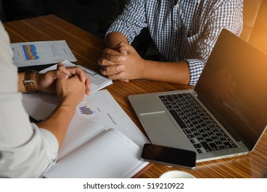 Two Hands Of Serious Business People Discussion And Negotiation During Meeting. On Office Desk Have Laptop And Smartphone, Hands-on Desk, Clasps Hands Firmly, Vintage And Dark Style. Business Concept