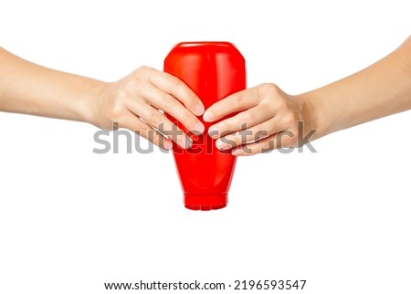 Two hands are squeezing a bottle of ketchup. Squeeze out the ketchup. Isolate on a white background. Squeezing a red plastic bottle.