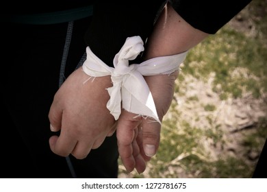 Two Hands Tied By A Ribbon. Male And Female Hand Tied With White Ribbon For Team Building