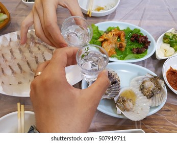 Two hands toasting Korean distilled spirits