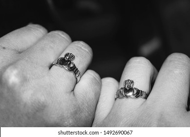 Two hands together with Claddagh rings, black and white; a traditional Irish ring which represents love, loyalty, and friendship