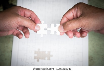 two hands try to put the last piece of jigsaw puzzle to complete the mission - Shutterstock ID 1007316943