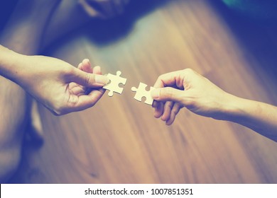 two hands trying to connect couple puzzle piece  Jigsaw alone wooden puzzle Teamwork, partnership, business idea, cooperation management concept - Shutterstock ID 1007851351