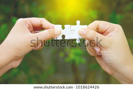 two hands trying to connect couple puzzle piece with trees background, jigsaw puzzle with sunlight effect, Business solutions, success and strategy concept