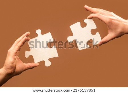 Two hands trying to connect couple puzzle piece on gray background. Teamwork concept. Closeup hand of connecting jigsaw puzzle. Holding puzzle. Business solutions, success and strategy concept.