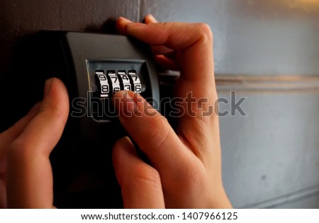 Two hands trying to enter the digits of the secret code in order to open the key locker and the security door. Introduce a 4-digits code to get the keys from a vacation rental apartment in a touristic
