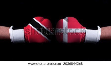 Two hands of wearing boxing gloves with Denmark and Trinidad and Tobago flag. Boxing competition concept. Confrontation between two countries