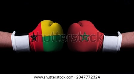 Two hands of wearing boxing gloves with Morocco and Guinea-Bissau flag. Boxing competition concept. Confrontation between two countries