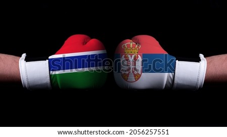 Two hands of wearing boxing gloves with Serbia and Gambia flag. Boxing competition concept. Confrontation between two countries