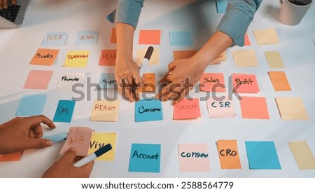 Two hands work on a white table filled with colorful sticky notes for collaborative planning and strategy development for business initiatives and projects. SACTR