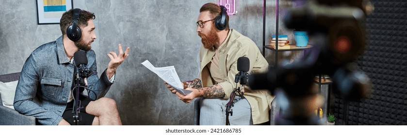 two handsome bearded men in casual attires with headphones talking actively during podcast, banner - Powered by Shutterstock