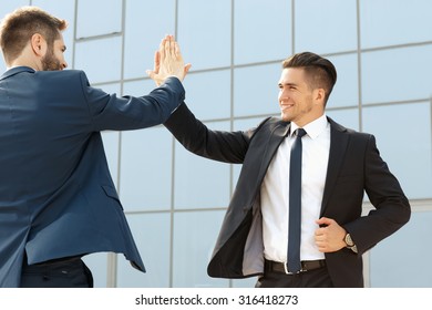 Two Handsome Business Colleagues High Fiving Outdoors