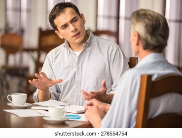 Two handsome businessmen  sitting at the wooden table in urban cafe and discussing important project. - Powered by Shutterstock