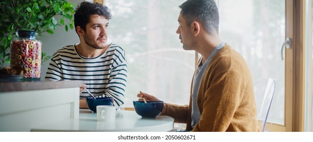 Two Handsome Friends are Eating Colorful Breakfast Cereal in Cozy Kitchen in Stylish Apartment. Young Adult Gay Couple Have a Conversation While Eating Healthy Nutricious Food in the Morning. - Powered by Shutterstock