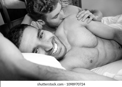 Two Handsome Gay Men, Nude In Bed Together Cuddling And Smiling One Of Them Has Visible Pecs And Defined Abs