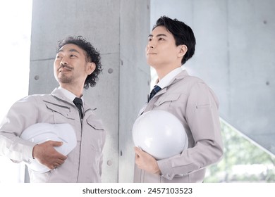 Two handsome looking up workers with helmets Image of building construction management and maintenance inspection
