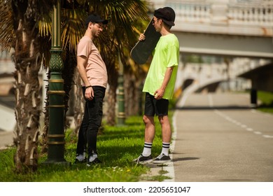 Two Handsome Male Friends Are Discussing Something Under The Trees