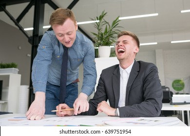 Two Handsome Young Business Men Work On Laptop In The Office And Laugh