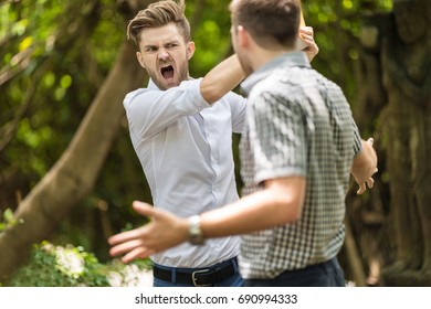 Two Handsome And Young Furious Men Fighting With Each Other In The Garden.