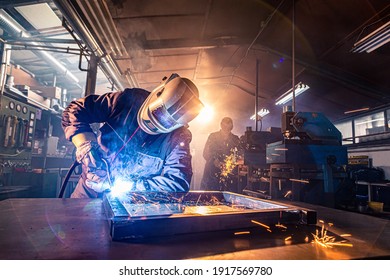 The two handymen performing welding and grinding at their workplace in the workshop, while the sparks "fly" all around them, they wear a protective helmet and equipment. - Shutterstock ID 1917569780