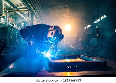 The two handymen performing welding and grinding at their workplace in the workshop, while the sparks "fly" all around them, they wear a protective helmet and equipment. - Powered by Shutterstock