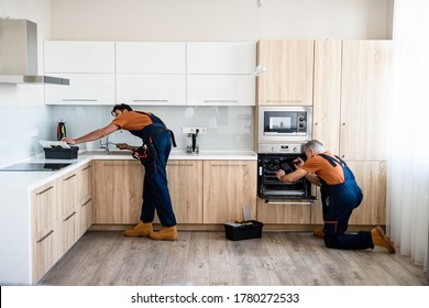 Two handymen, workers in uniform fixing, installing furniture and equipment in the kitchen, using screwdriver indoors. Furniture repair and assembly concept. Horizontal shot - Powered by Shutterstock