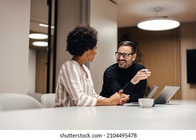 Two happy adult colleagues, having a conversation at the end of their shift. - Shutterstock ID 2104495478