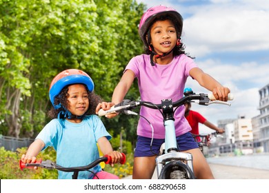 Two Happy African Girls Riding Bikes In City