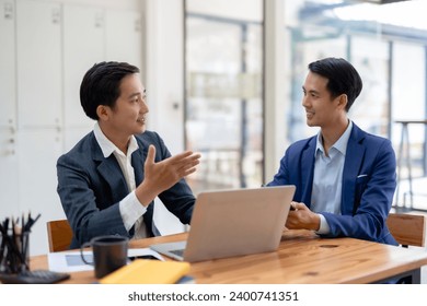 Two happy asian businessman talking and consulting working together with laptop computer  in the office. - Powered by Shutterstock