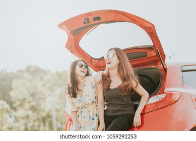 Two Happy Asian Girl Best Friends Traveler Laughing And Smiling While Sitting In Red Car Trunk 