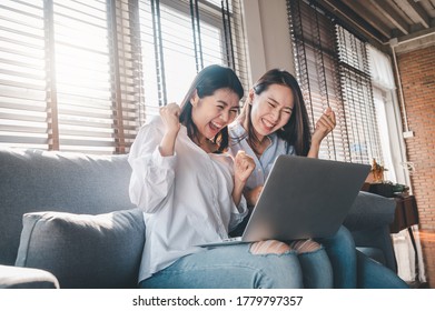 Two Happy Asian Women Best Friends Excited While Using Laptop At Home In Living Room