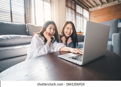 Two Happy Asian Women Best Friends In Casual Wear Excited And Surprised While Using Laptop At Home In Living Room