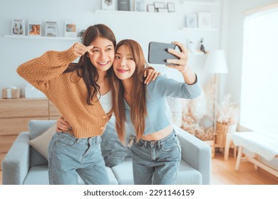 Two happy asian women blogger shooting social media stories or video calling in mobile app and enjoying rest in living room at home. selfie - Powered by Shutterstock