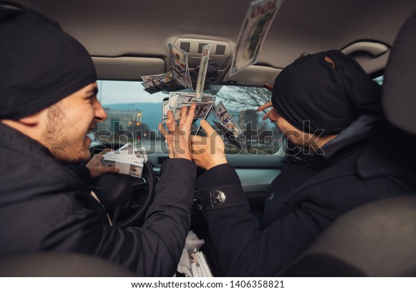 Two happy bank\
robbers celebrating their successful hit while sitting in the car\
they used for the robbery.