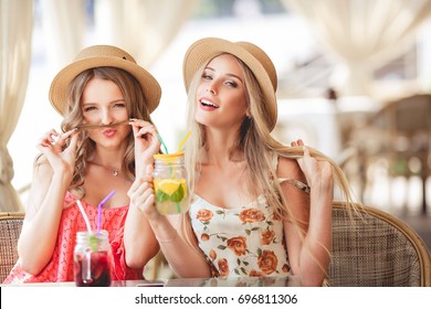 Two Happy Beautiful Girls Having Fun In A Cafe In Sunny Summer Day. Lifestyle, Travel Concept.