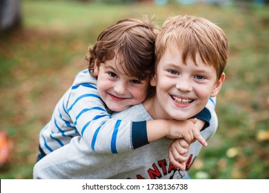 Two happy boys, happy brothers who are smiling happily together. Brothers play outdoors in summer, best friends. Little brother with brother on his back. Two brothers in the woods. Fraternal relations - Shutterstock ID 1738136738
