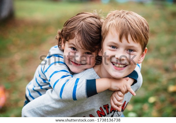 Two happy boys, happy brothers who are smiling
happily together. Brothers play outdoors in summer, best friends.
Little brother with brother on his back. Two brothers in the woods.
Fraternal relations