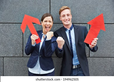 Two Happy Business People Cheering With Big Red Arrows Pointing Up